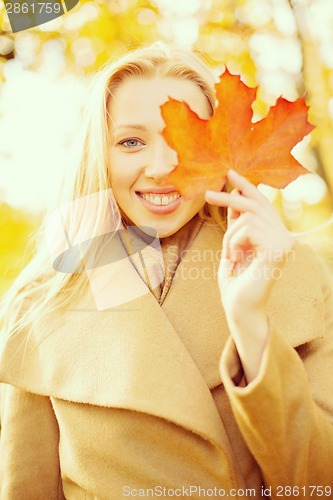 Image of woman with red marple leaf in the autumn park