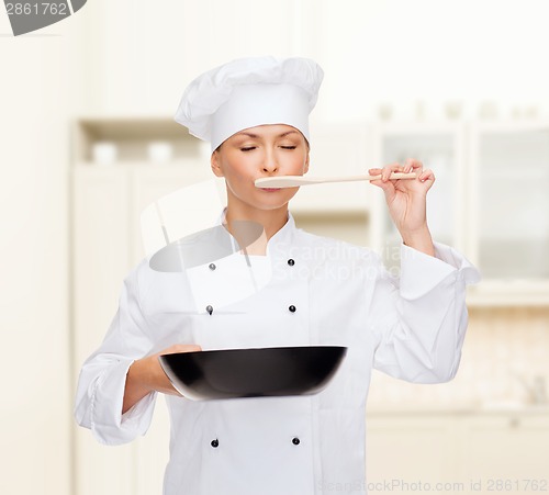 Image of smiling female chef with pan and spoon