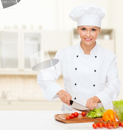 Image of smiling female chef chopping vegetables