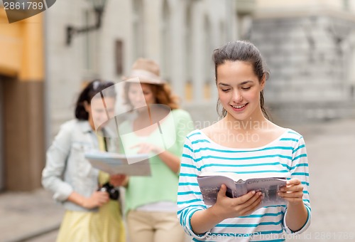 Image of smiling teenage girls with city guides and camera