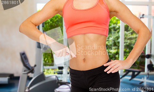 Image of close up of woman pointing finger at her six pack