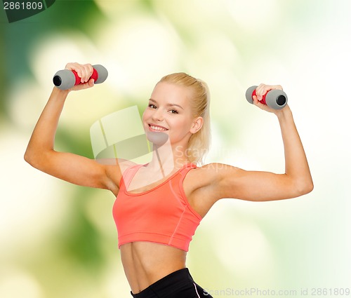 Image of smiling beautiful sporty woman with dumbbells