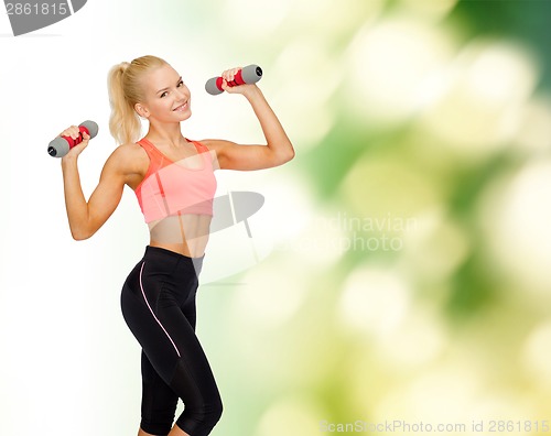 Image of smiling beautiful sporty woman with dumbbells