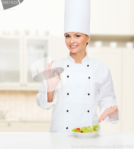 Image of smiling female chef with salad on plate