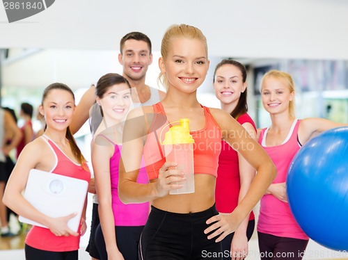 Image of smiling sporty woman with protein shake bottle