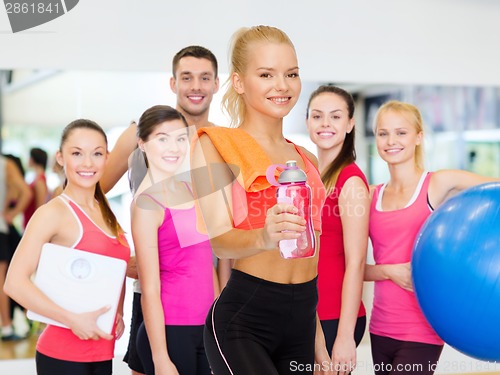 Image of smiling sporty woman with water bottle and towel