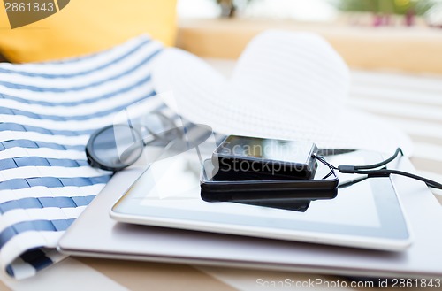 Image of close up of tablet pc and smartphone on beach