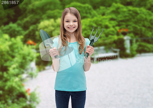 Image of smiling little girl with rake and scoop