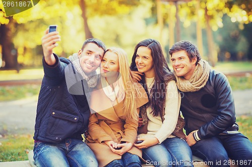 Image of group of friends with photo camera in autumn park