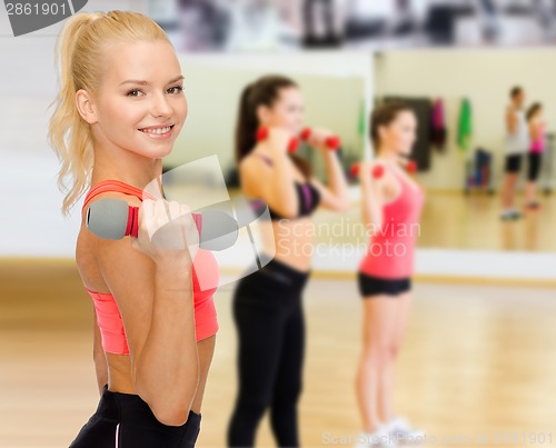 Image of smiling beautiful sporty woman with dumbbell