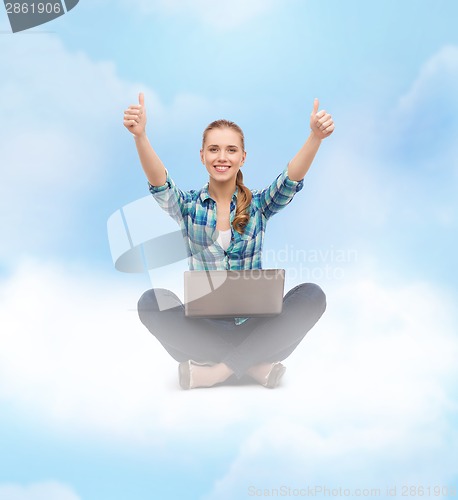 Image of smiling woman with laptop and showing thumbs up