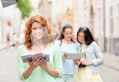 Image of smiling teenage girls with city guides and camera