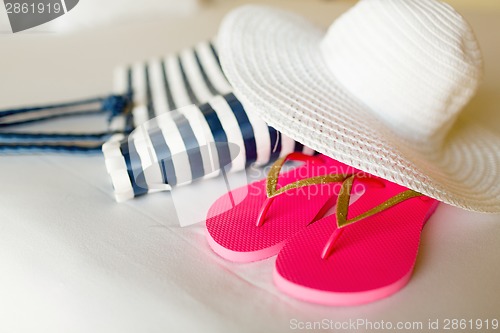 Image of close-up of beach bag, hat and flip-flops on bed