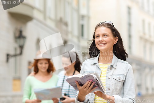 Image of smiling teenage girls with city guides and camera
