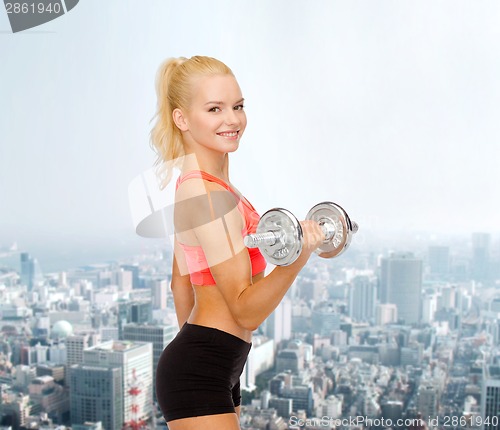 Image of young sporty woman with heavy steel dumbbell