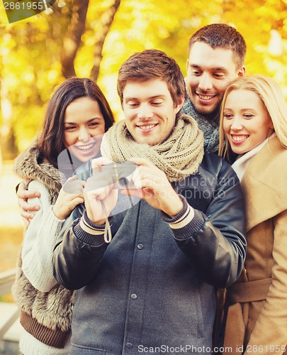 Image of group of friends with photo camera in autumn park