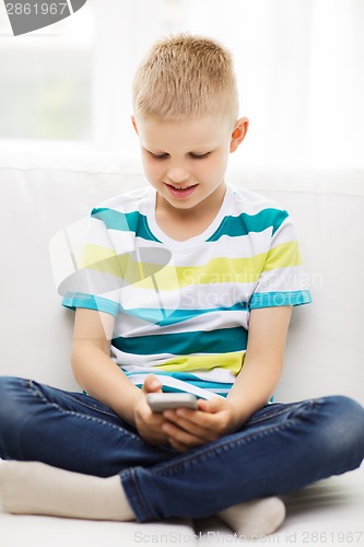 Image of smiling little boy with smartphone at home