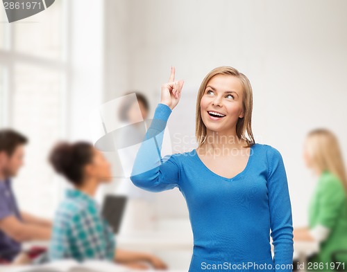 Image of smiling woman pointing her finger up