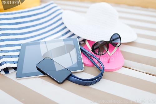 Image of close up of tablet pc and smartphone on beach