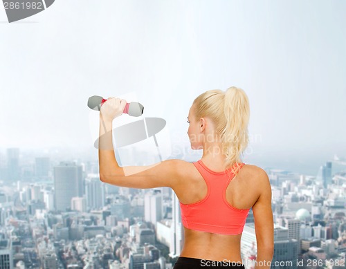 Image of young sporty woman with light dumbbell