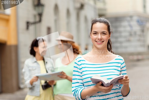 Image of smiling teenage girls with city guides and camera