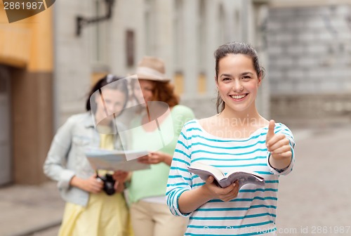 Image of smiling teenage girls with city guide and camera