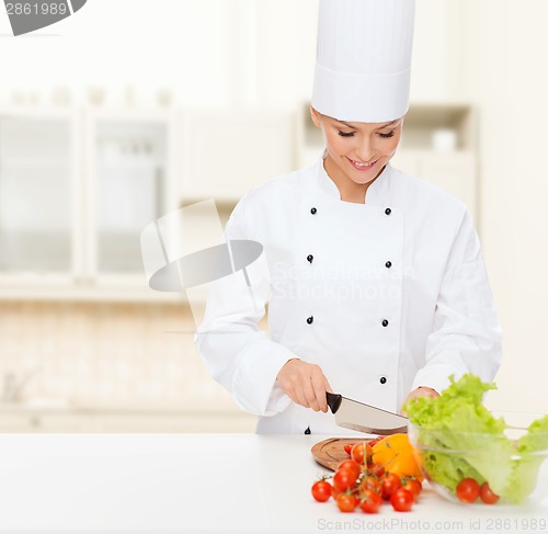 Image of smiling female chef chopping vegetables