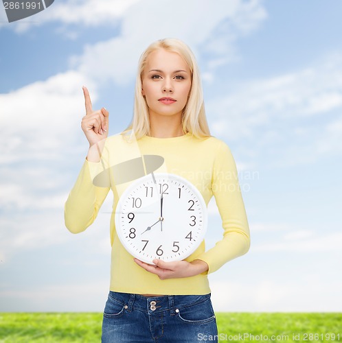 Image of student with wall clock and finger up