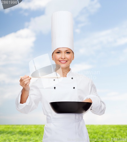 Image of smiling female chef with pan and spoon