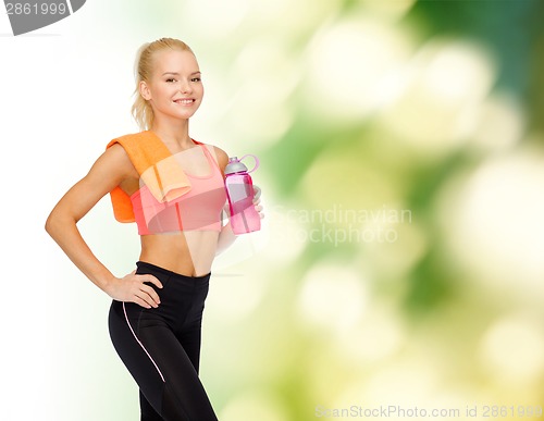 Image of smiling sporty woman with water bottle and towel