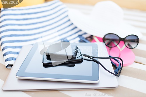 Image of close up of tablet pc and smartphone on beach