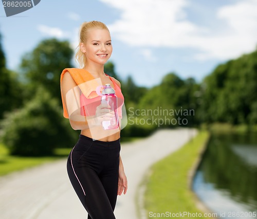 Image of smiling sporty woman with water bottle and towel