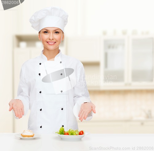 Image of smiling female chef with salad and cake on plates