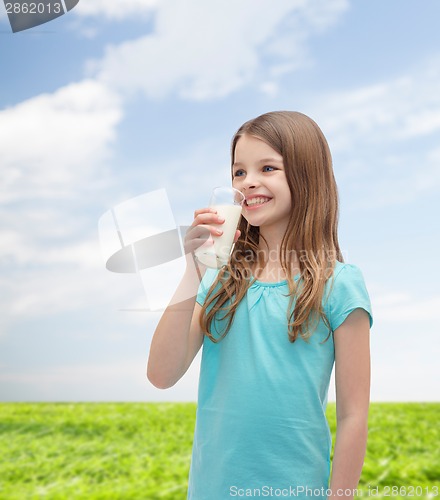 Image of smiling little girl drinking milk out of glass