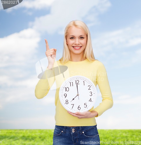 Image of student with wall clock and finger up