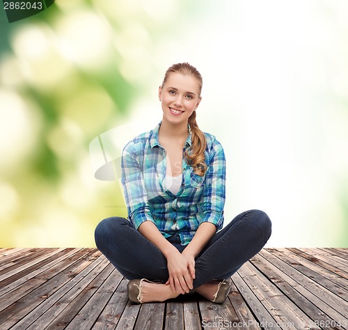 Image of young woman in casual clothes sitting on floor