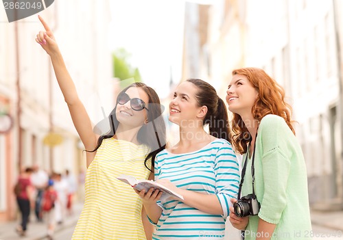 Image of smiling teenage girls with city guide and camera