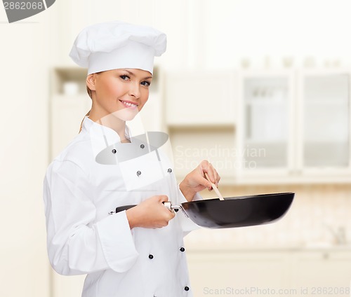 Image of smiling female chef with pan and spoon