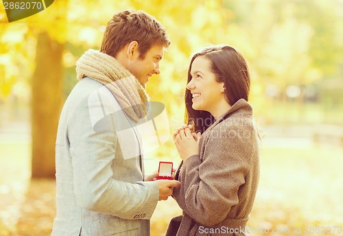 Image of man proposing to a woman in the autumn park