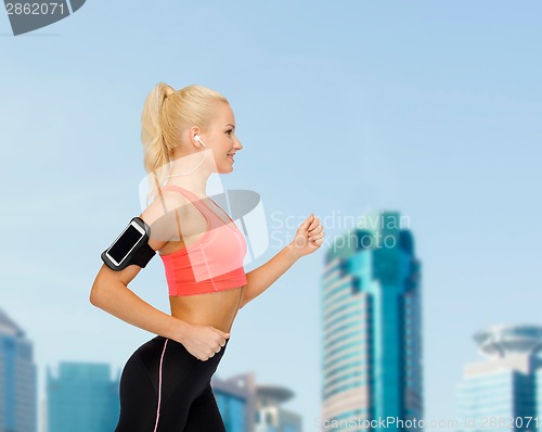Image of sporty woman running with smartphone and earphones