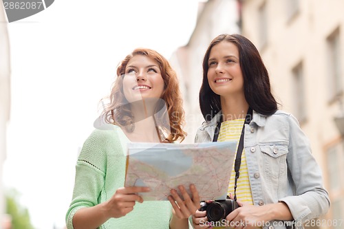 Image of smiling teenage girls with map and camera