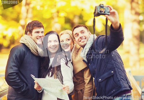 Image of group of friends with photo camera in autumn park