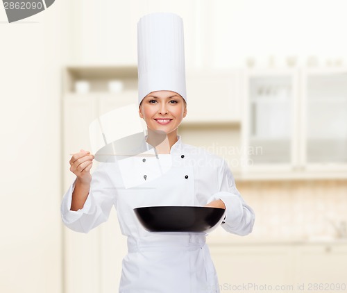 Image of smiling female chef with pan and spoon