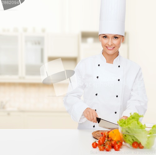 Image of smiling female chef chopping vegetables