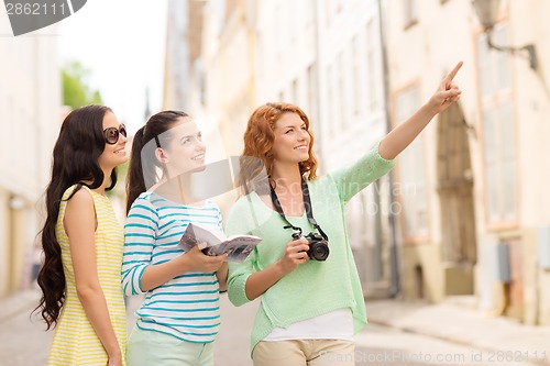 Image of smiling teenage girls with city guide and camera