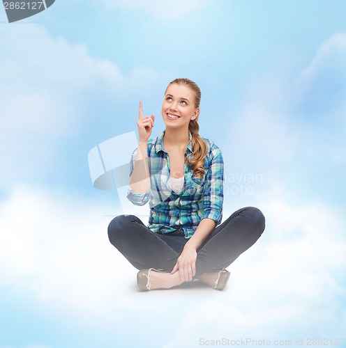 Image of smiling young woman pointing finger up