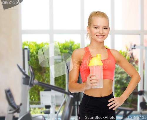 Image of smiling sporty woman with protein shake bottle