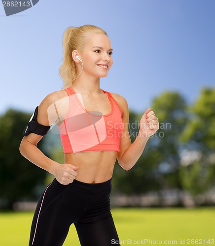 Image of sporty woman running with smartphone and earphones