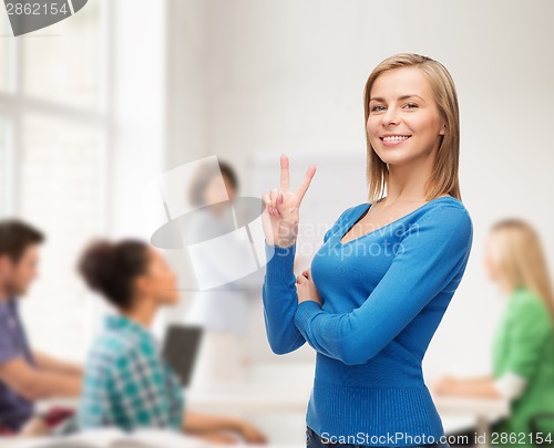 Image of smiling teenage girl showing v-sign with hand