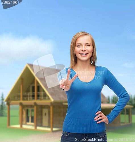 Image of smiling teenage girl showing v-sign with hand